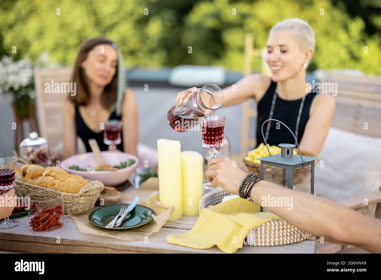 Junge, stilvolle Freunde bei einem festlichen Abendessen auf der Dachterrasse Stockfoto