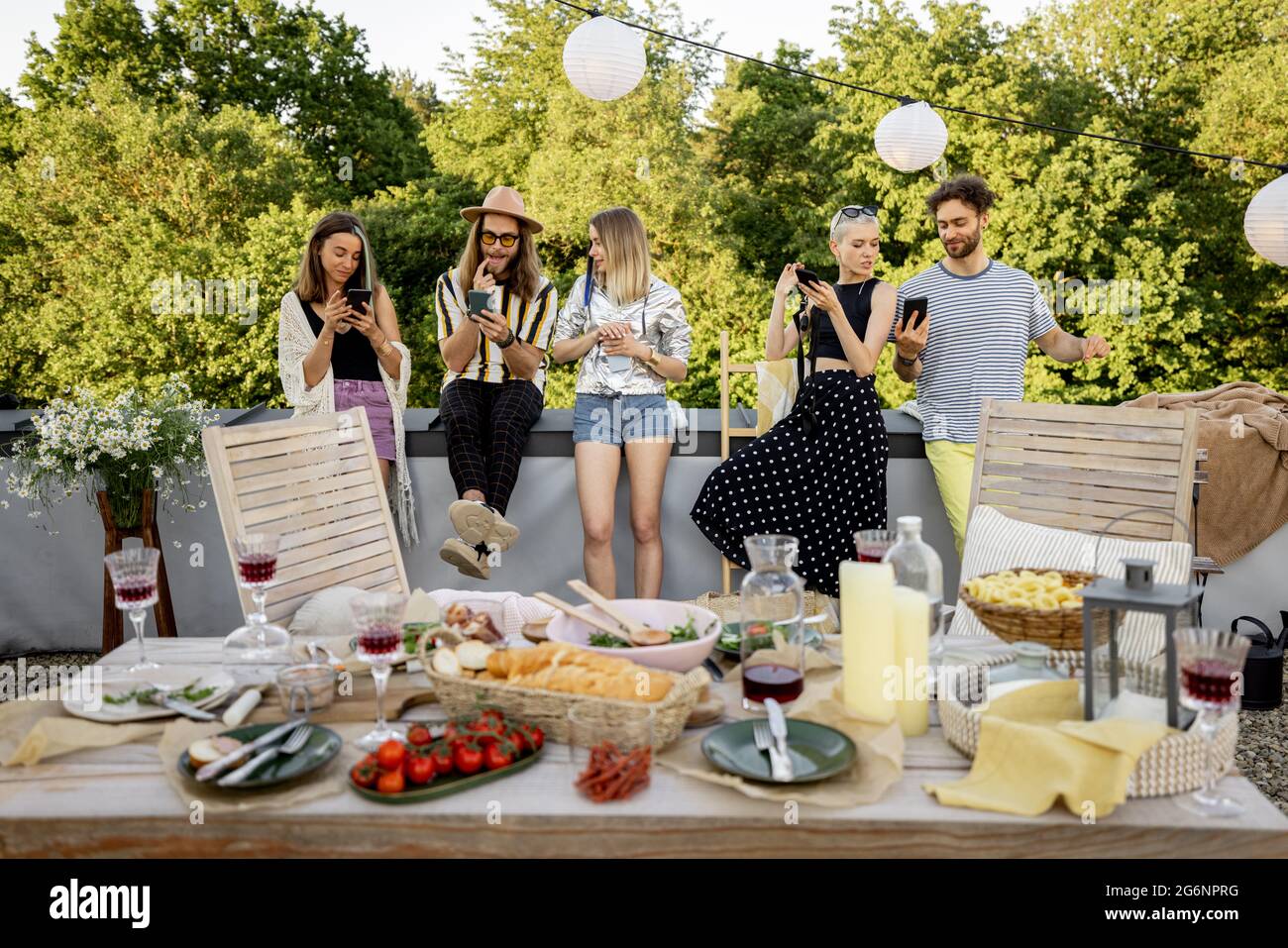 Menschen verbringen Zeit miteinander, sitzen getrennt in Smartphones auf Party im Freien Stockfoto