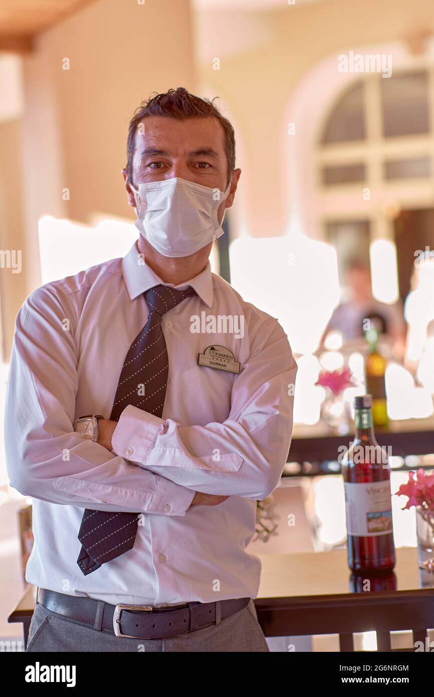 Kemer, Türkei - 23. Mai 2021: Barkeeper in Maske, weißes Hemd und Krawatte hinter einer Bar draußen. Hochwertige Fotos Stockfoto