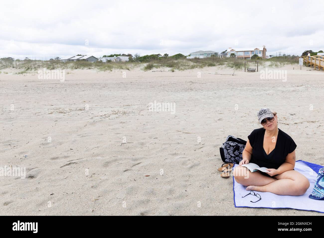 Eine Frau, die allein am Strand sitzt und ein Buch liest Stockfoto