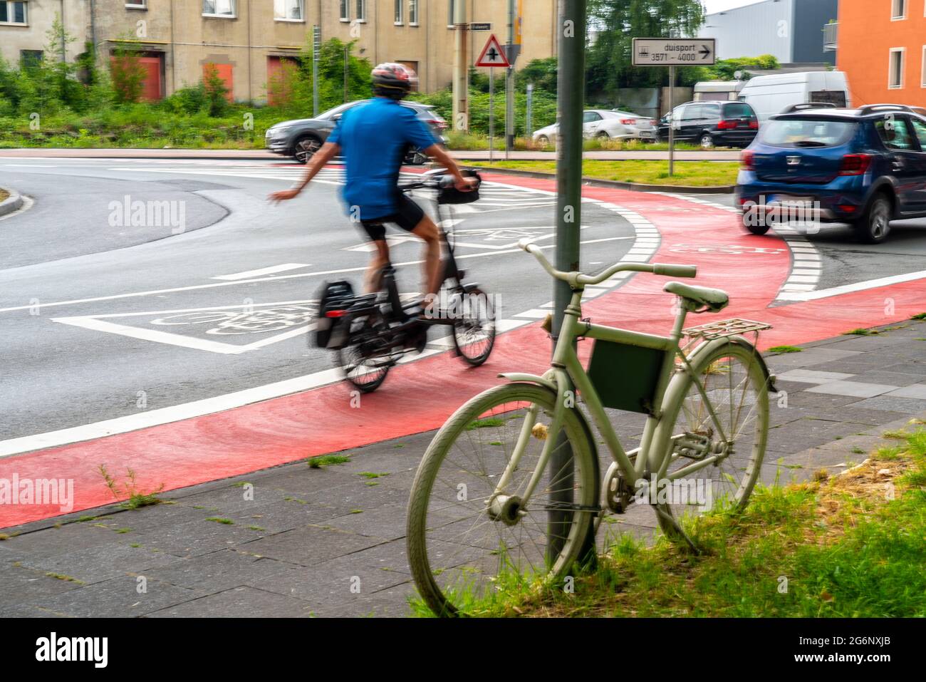 Weißes Fahrrad erinnert an einen tödlichen Unfall mit einem Radfahrer, rote Radweg markiert in einem innerstädtischen Kreisverkehr, um Fahrer darauf aufmerksam zu machen, dass auch Radfahrer Stockfoto