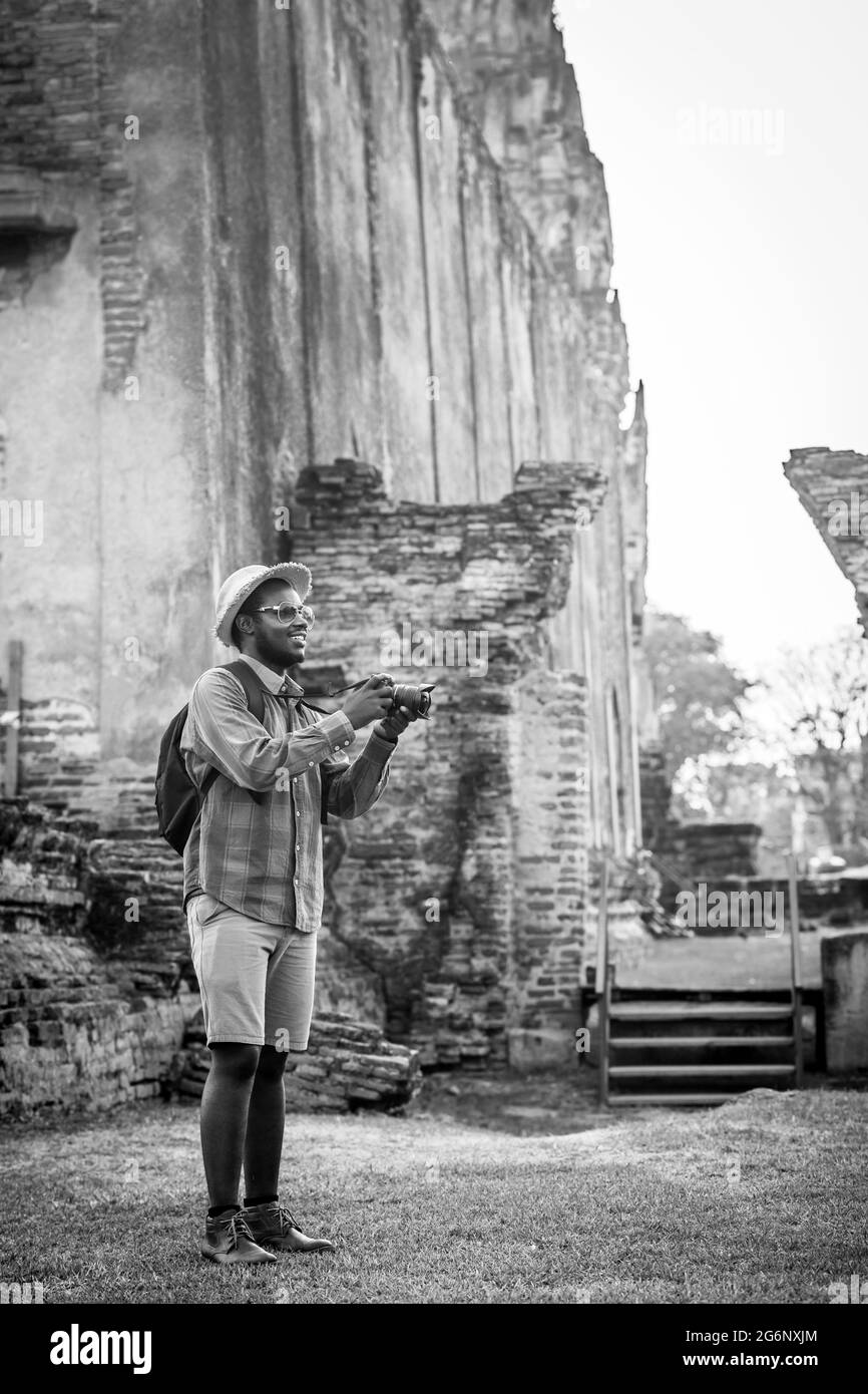 Afrikanischer männlicher Reisender macht sich glücklich, alte Landschaften mit wunderschönen alten asiatischen Gebäuden zu fotografieren Stockfoto