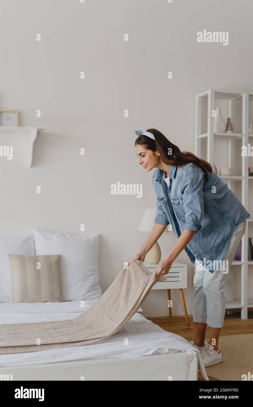 Junge Frau, die ihr Bett macht. Stockfoto