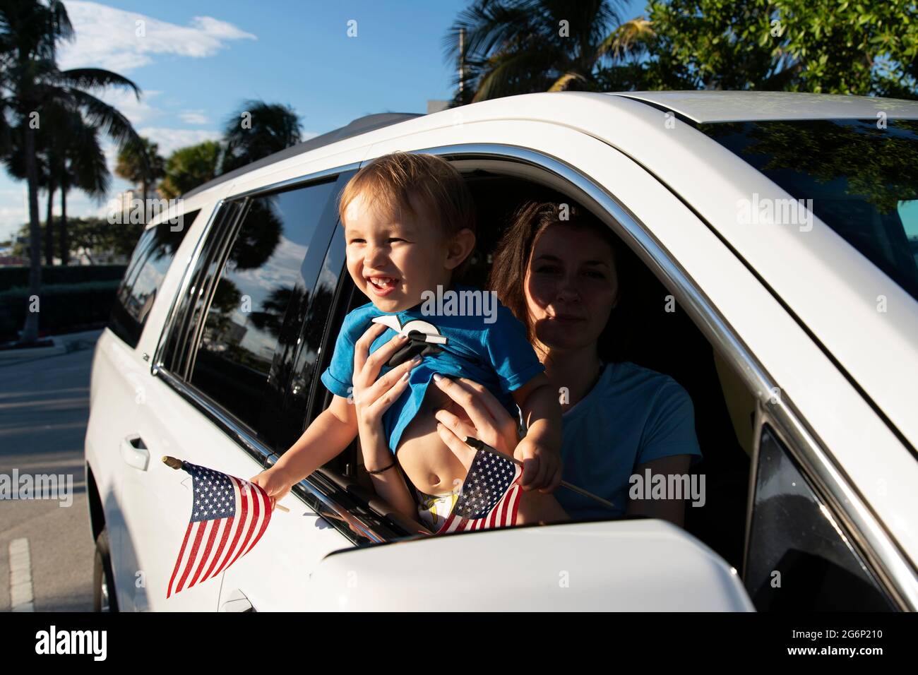 Ein Kleinkind winkt amerikanische Flaggen aus einem Autofenster Stockfoto