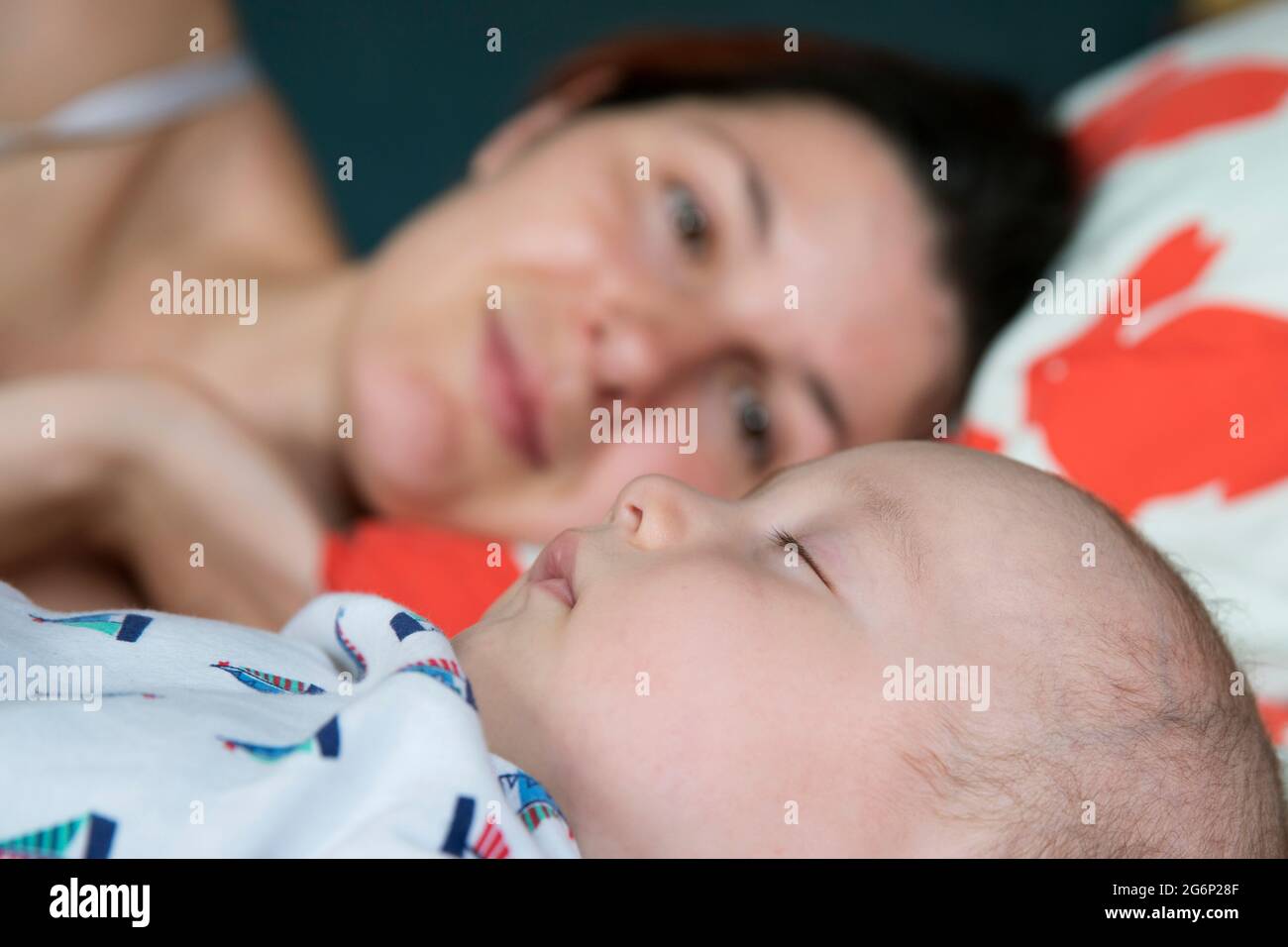Eine Mutter, die mit ihrem Baby auf einem Bett liegt Stockfoto