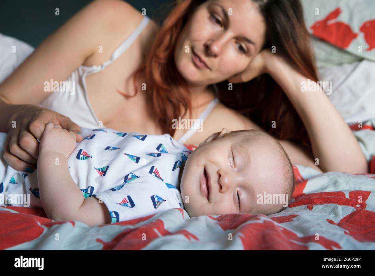 Eine Mutter, die mit ihrem Baby auf einem Bett liegt Stockfoto