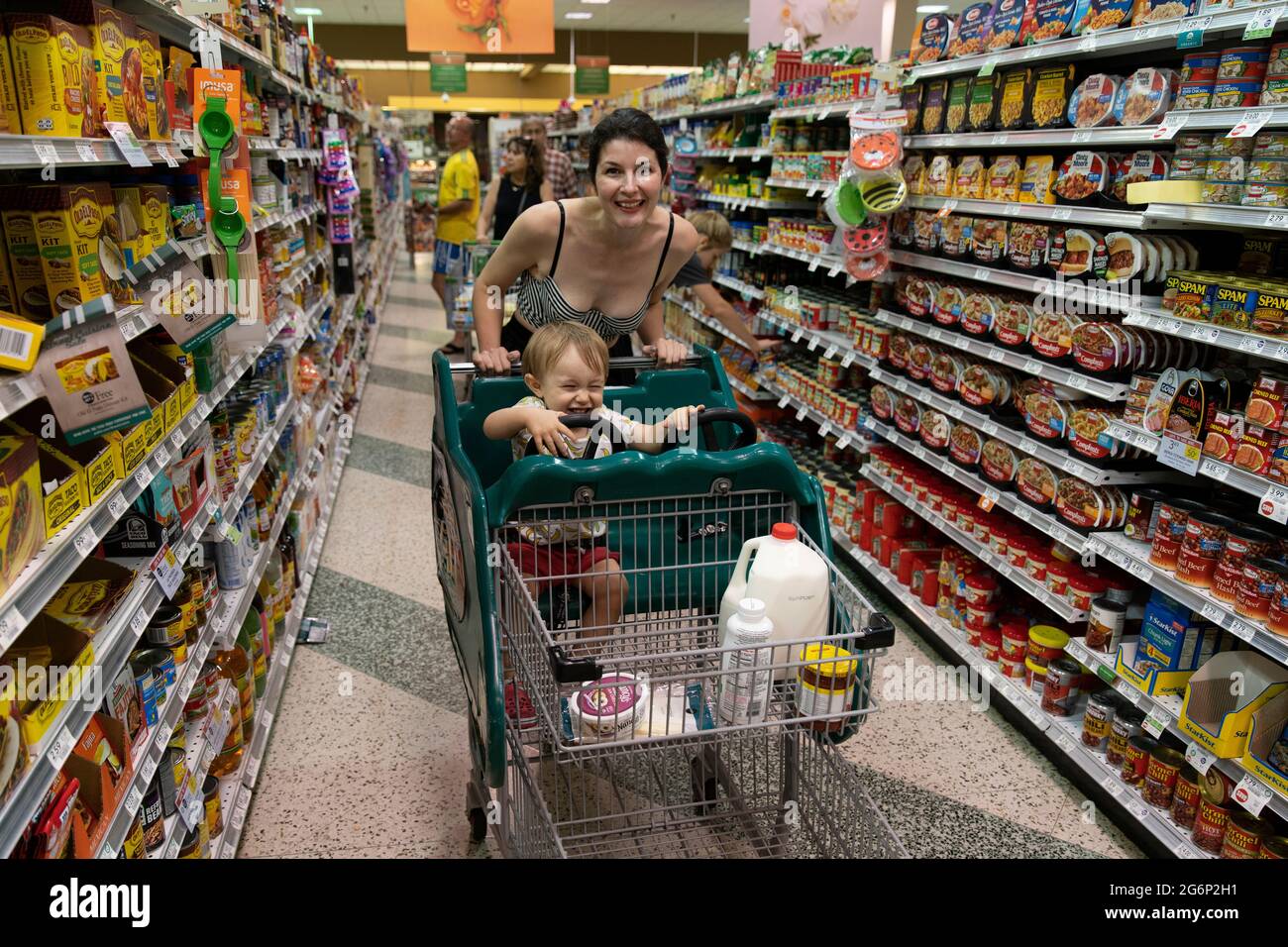 Eine Frau, die ihr Kind in einem Supermarkt in Florida in einen Trolley schiebt Stockfoto