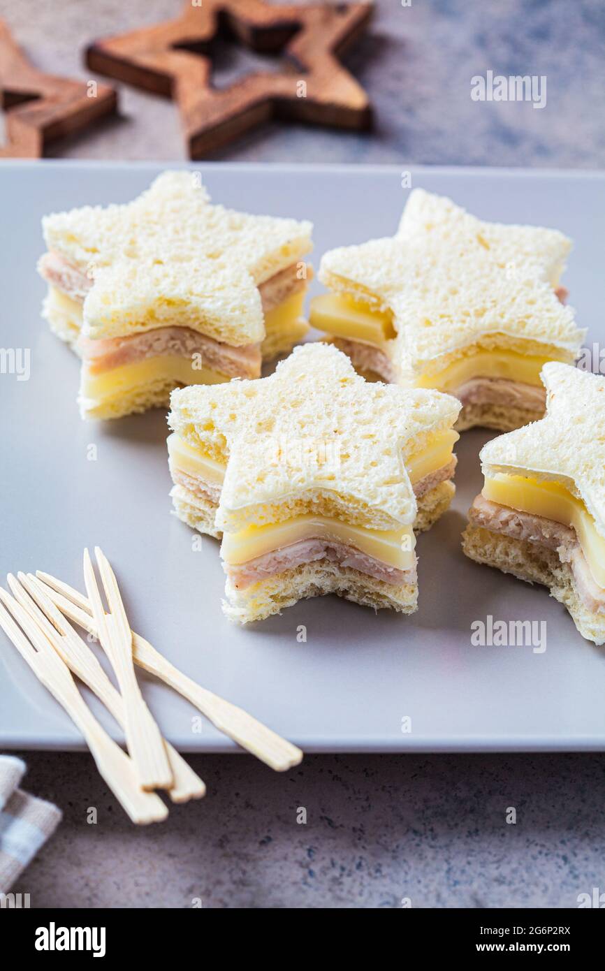 Christmas Snacks: Sternförmige Sandwiches mit Käse und Schinken auf einem grauen Teller. Festliches Food-Konzept. Stockfoto