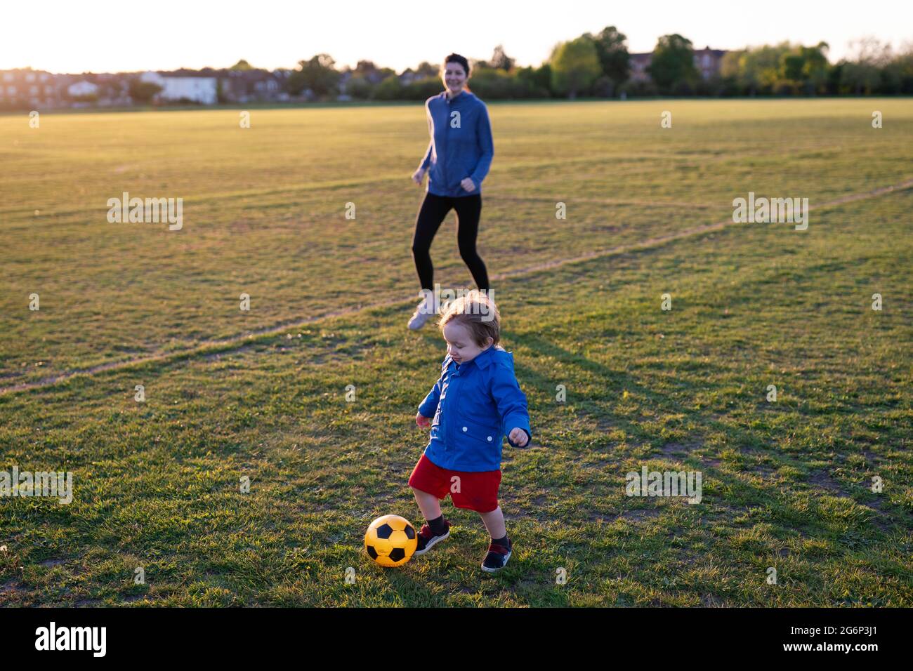 Eine Mutter, die mit ihrem kleinen Sohn Fußball spielt Stockfoto