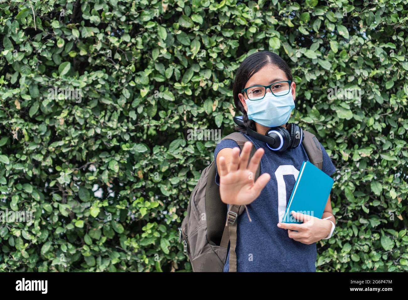 Schüler trägt Schutzmaske mit ausgestrecktem Arm Stockfoto