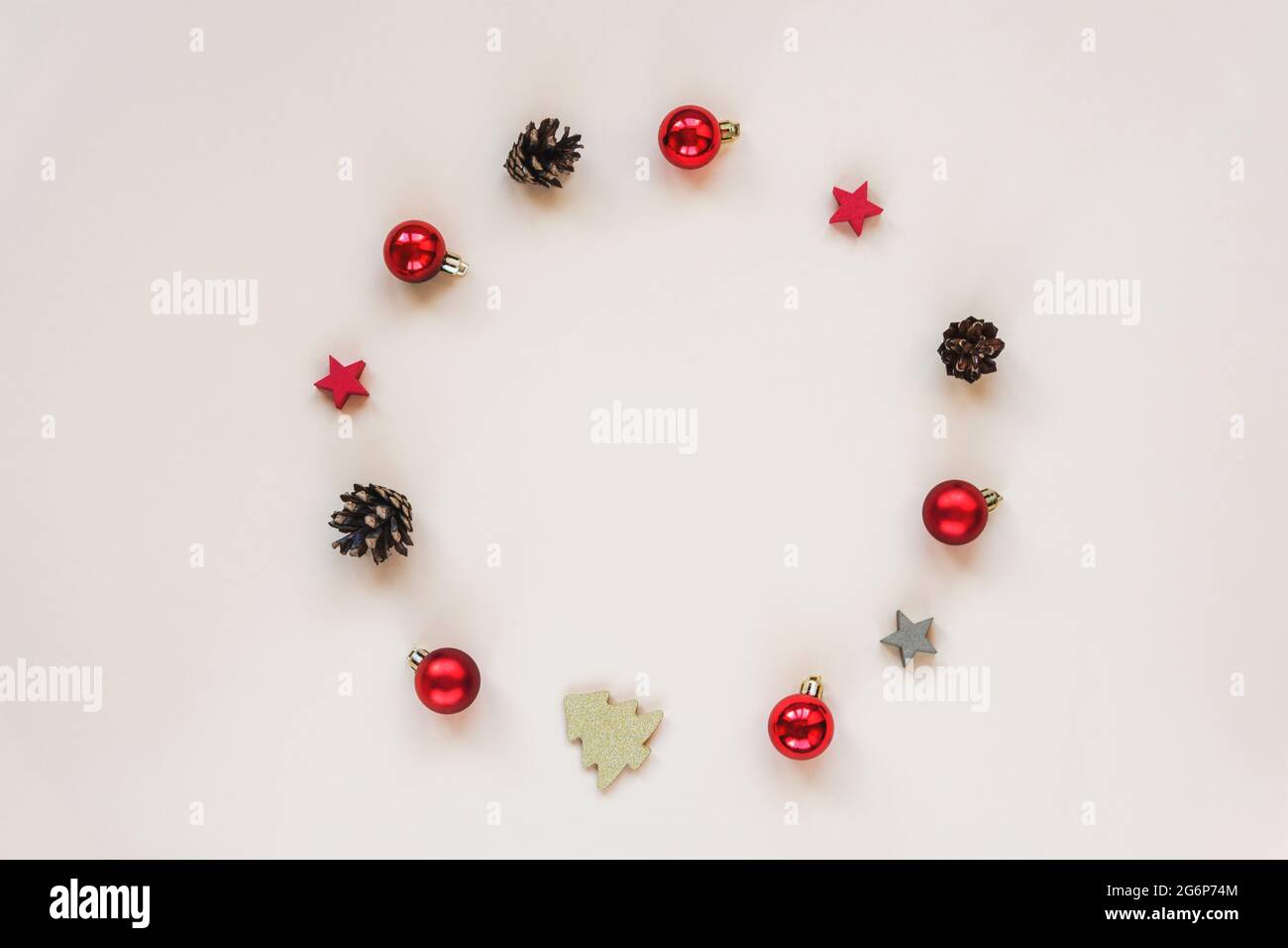 Weihnachtliche festliche Hintergrundkegel, rote Weihnachtskugeln und Dekorationen in Form eines Kreises auf beigem Hintergrund mit Kopierraum. Draufsicht, flach Stockfoto