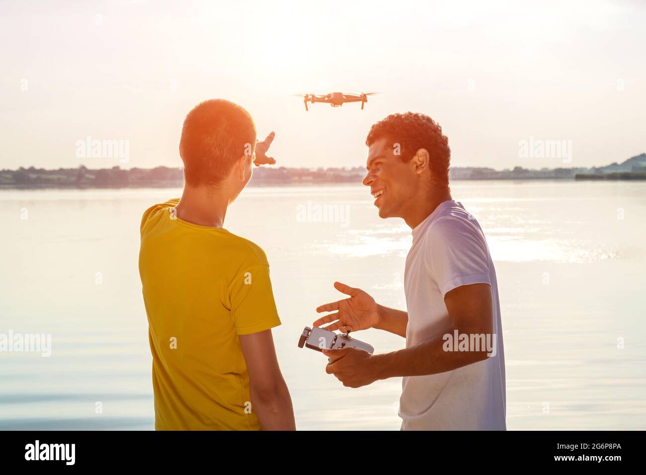 Zwei Freunde operieren Drohne mit Controller in der Nähe des Flusses stehen Stockfoto