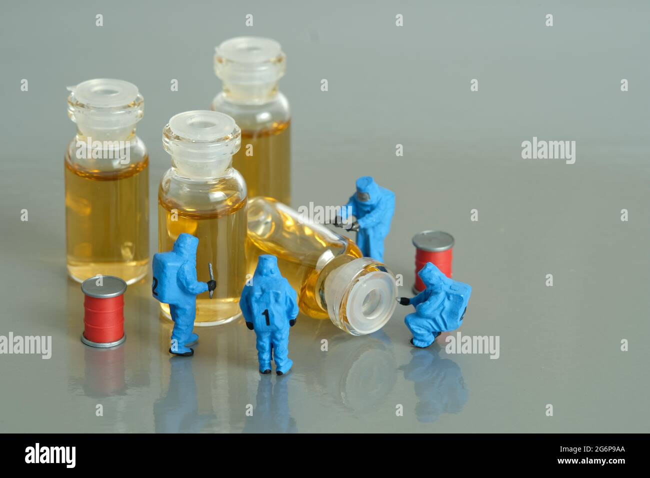 Miniatur Menschen Spielzeug Figur Fotografie. Test mit klinischen Impfstofftests. Eine Gruppe von Sanitätern mit einem Hasmatanzüge, der Impfampulle testet. Bildfoto Stockfoto