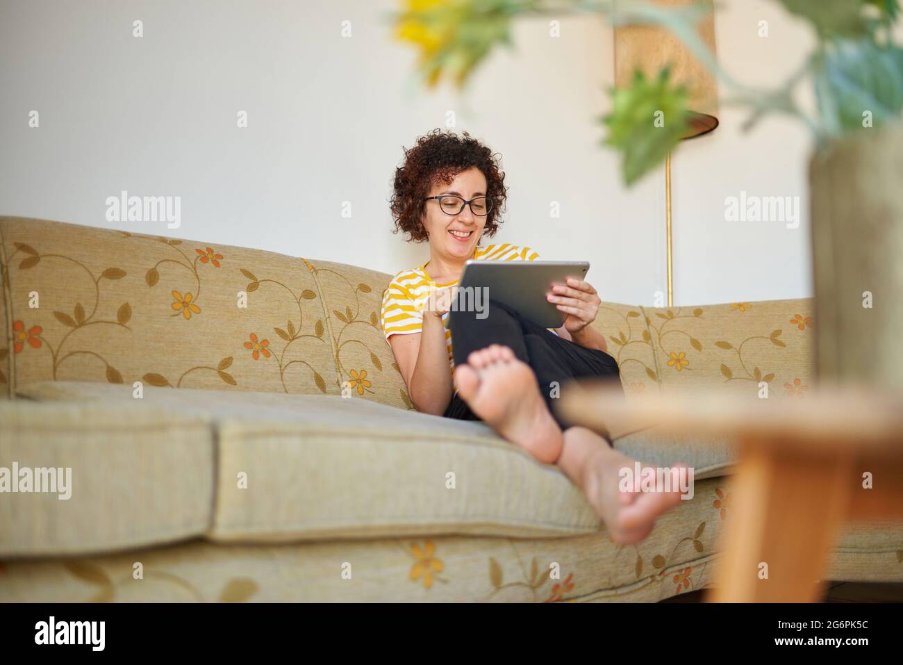 Frau sitzt auf dem Sofa mit digital-Tablette Stockfoto