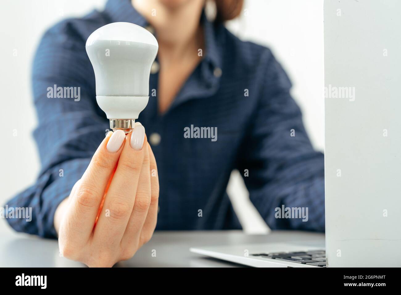 Weibliche Hand, die eine Glühbirne über dem Tisch hält Stockfoto
