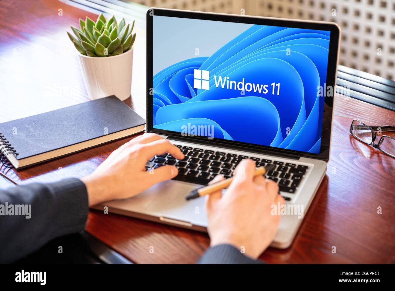 Griechenland Athen, Juli 8 2021. Mann arbeitet mit einem Laptop, Windows 11 neues Microsoft-Betriebssystem auf dem Computerbildschirm, Büro Schreibtisch Hintergrund. Stockfoto