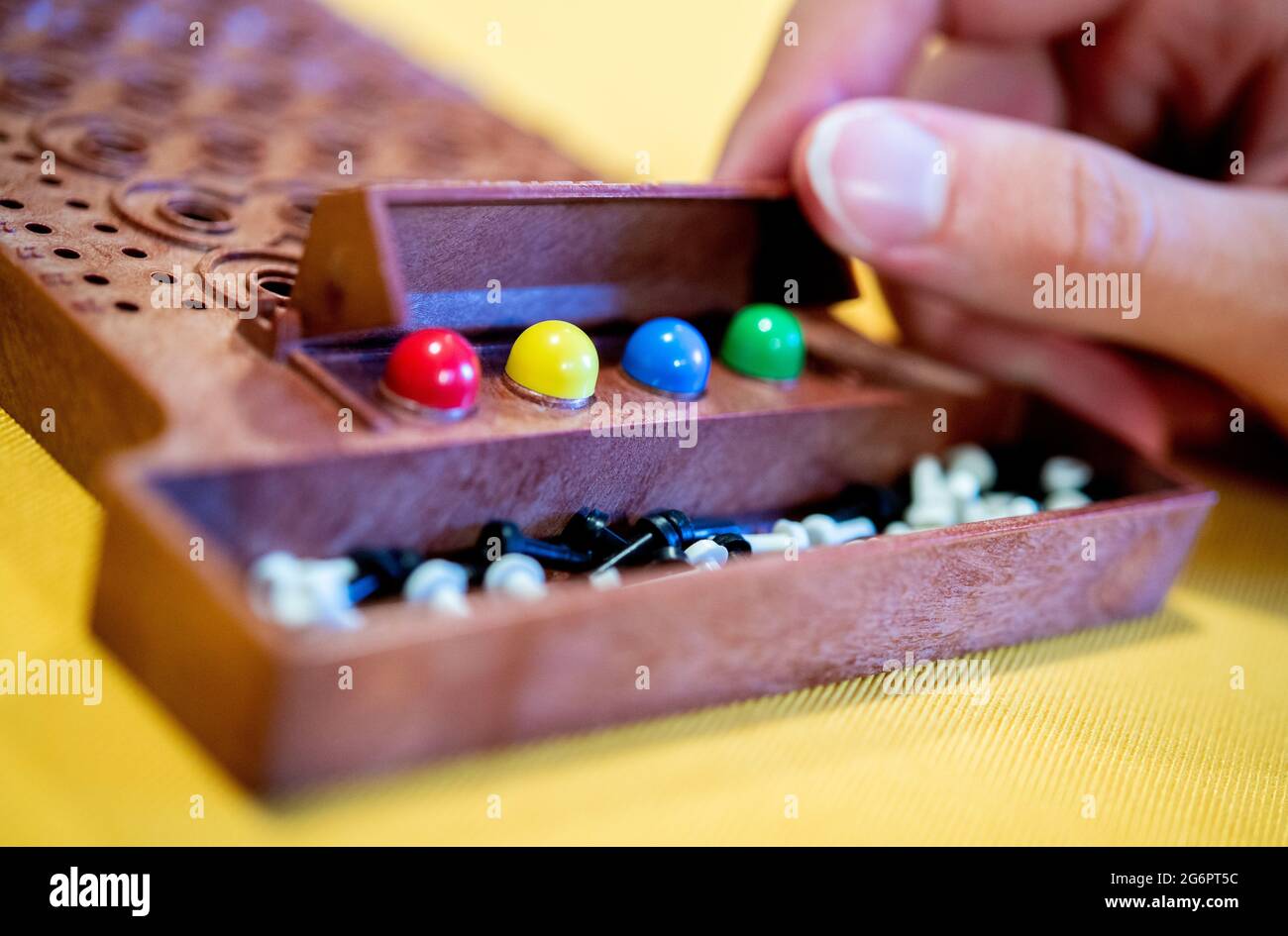 Wardenburg, Deutschland. Juli 2021. Während einer Runde des Spiels „Mastermind“ legt ein Spieler farbige Spielsteine auf das Spielfeld. Mastermind ist ein Logikspiel für zwei Personen, bei dem eine Farbfolge durch aufeinanderfolgende Vermutungen bestimmt werden soll. Quelle: Hauke-Christian Dittrich/dpa/Alamy Live News Stockfoto