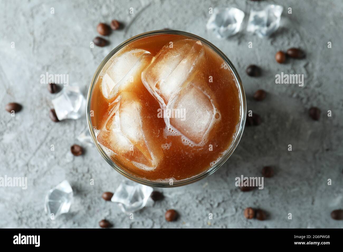 Glas Eiskaffee, Bohnen und Eis auf einem grauen Tisch mit Struktur Stockfoto
