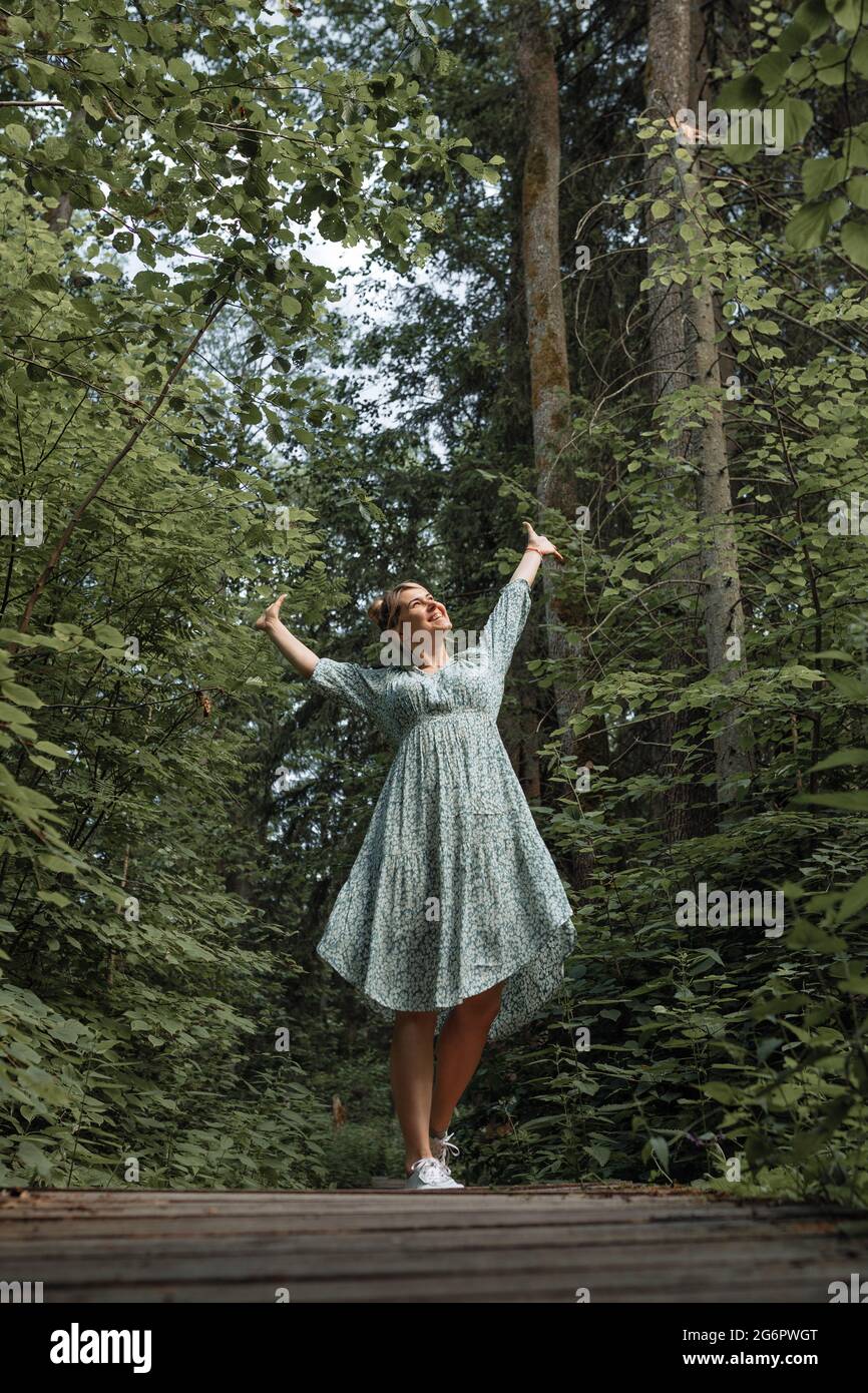 Kaukasische Frau atmet frische Luft im Wald und hebt ihre Hände hoch. Lifestyle-Konzept und aktiver Lifestyle Stockfoto