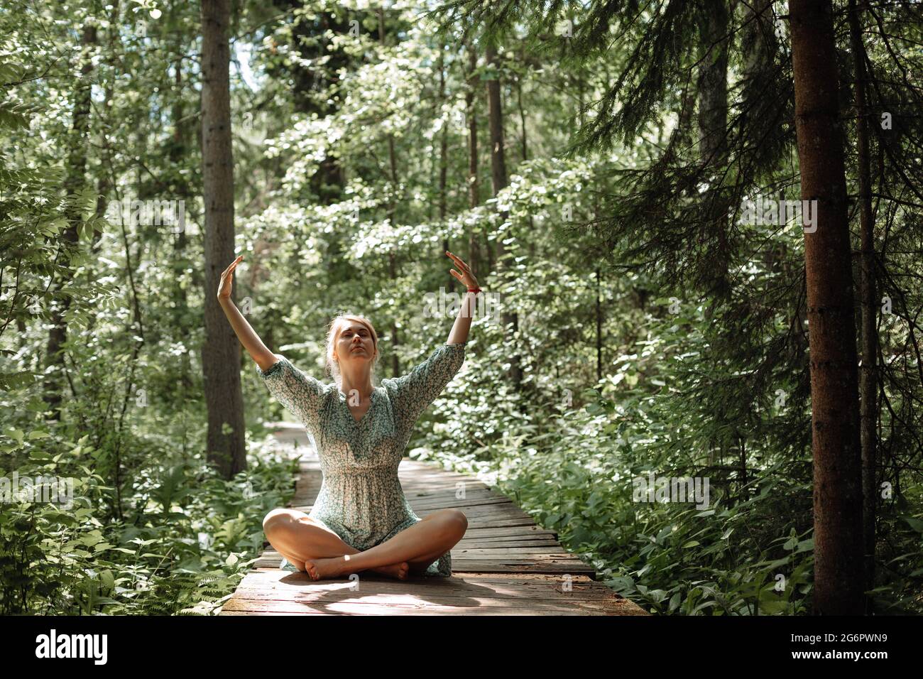 Frau macht Atemübungen im Wald an der frischen Luft. Konzept eines gesunden Lebensstils, Einsamkeit und Verschmelzung mit der Natur. Hochwertige Fotos Stockfoto