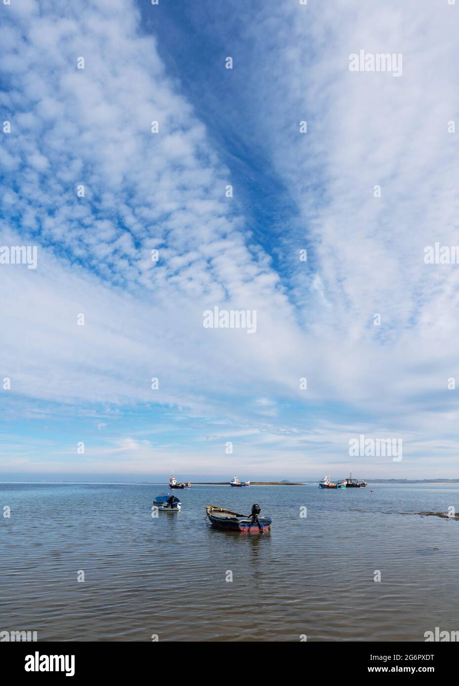 Panoramablick auf kleine Fischerboote, die im Meer mit Wolken vor Anker liegen, Holy Island, Northumberland, Großbritannien Stockfoto