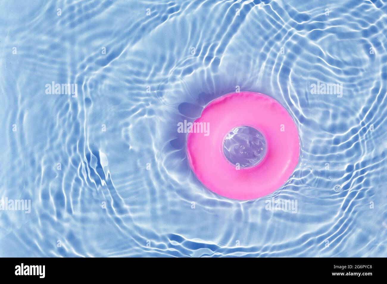 Pink Pool Float Ring schwimmt in einem erfrischenden blauen Pool. Draufsicht Stockfoto