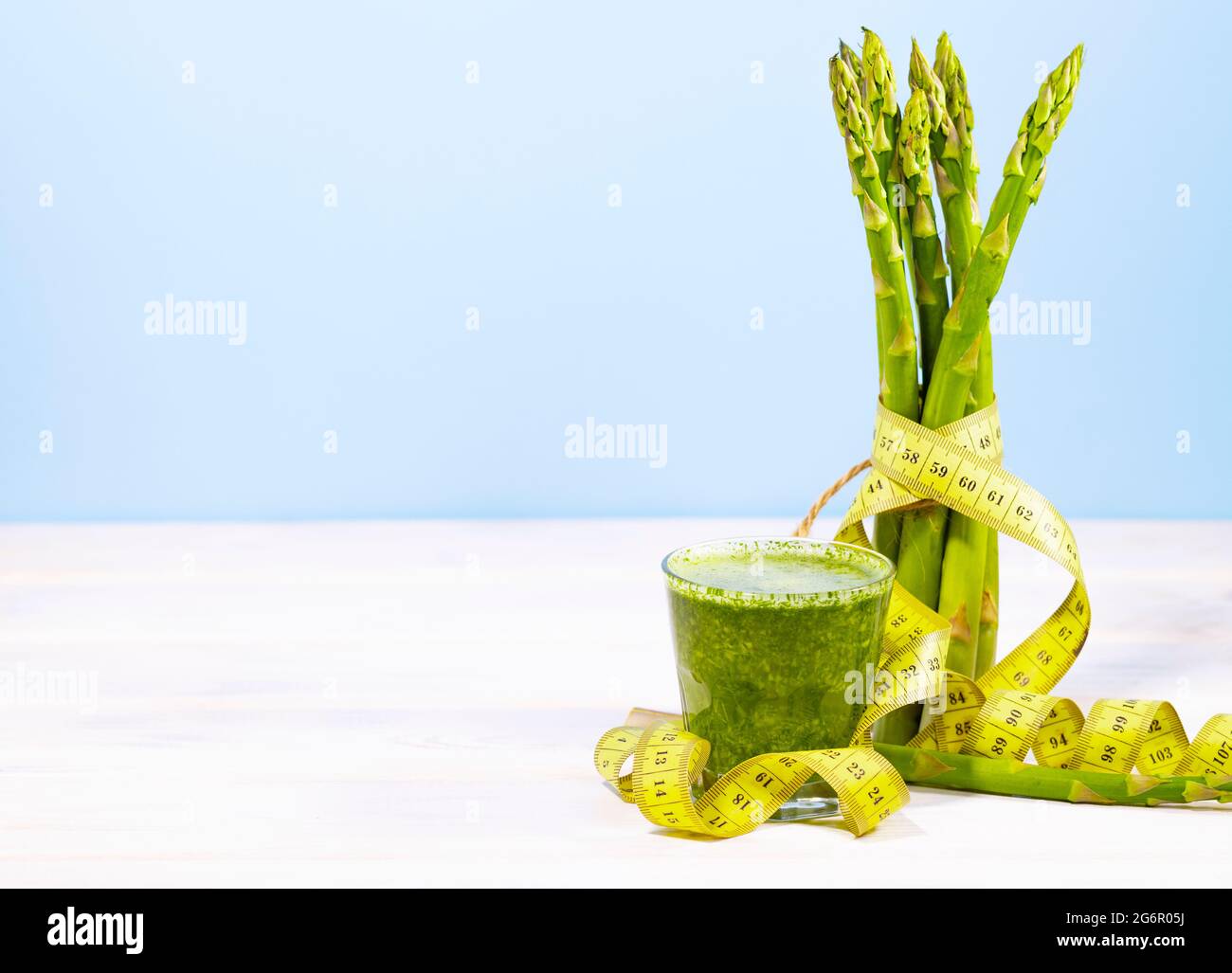 Bund frischer Spargel auf blauem Hintergrund mit Maßband. Ketogene Ernährung mit Vitaminen und Zellulose. Grünes Gemüse. Speicherplatz kopieren. Sauber e Stockfoto