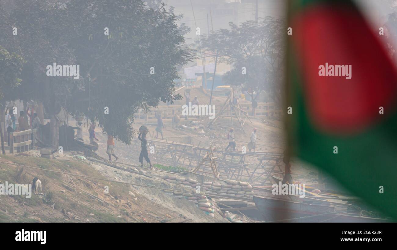 Eine menschliche Kette von Trägern trägt Kohle, Sand und Kies von den Bargen, die an der Aminbazar Landing Station am Buriganga River außerhalb von Dhaka festgemacht sind. Bangladesch absolviert derzeit den Abschluss der LDC-Kategorie (am wenigsten entwickelte Länder), was zum großen Teil der extrem harten Arbeit billiger Arbeitskräfte zu verdanken ist. Ein Portier macht zwischen 80 und 140 USD pro Monat, laut den Websites paylab.com und averagesalarysurvey.com Stockfoto