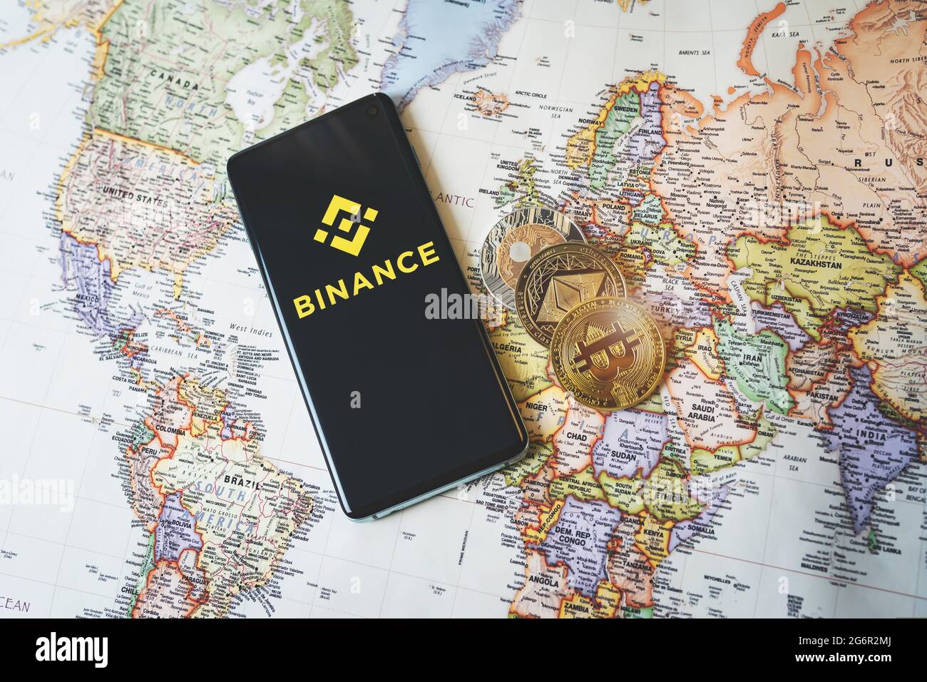 SWANSEA, Großbritannien - 8. JULI 2021: Binance App-Logo auf einem Smartphone und Krypto-Münzen Bitcoin, Ethereum und XRP auf einer Weltkarte. Beliebte Kryptowährungsexchang Stockfoto