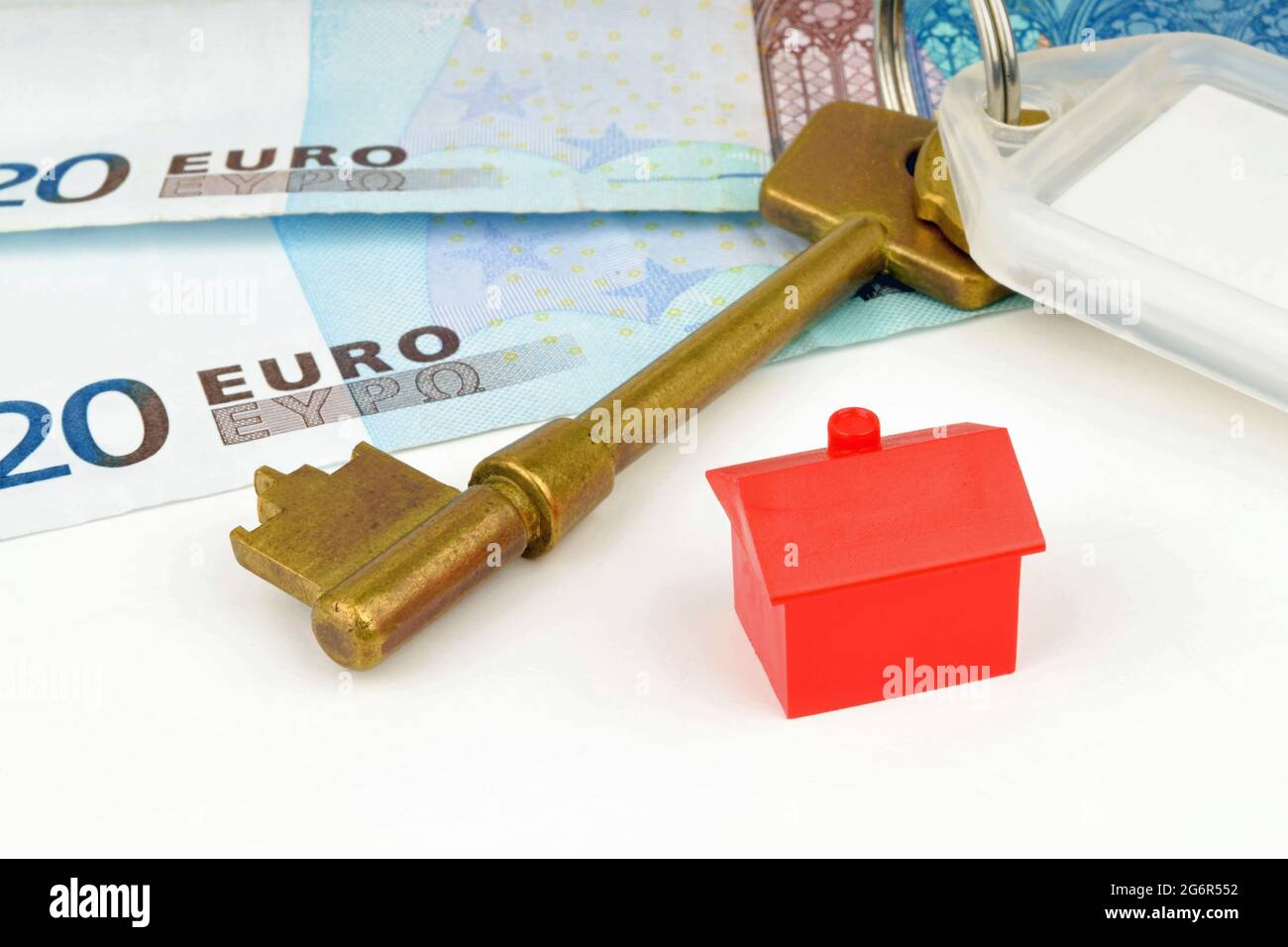 Ein Stillleben mit Schlüssel, Spielzeughaus und Euro-Währung. Ein Foto, das die Hausfinanzierung symbolisiert. Stockfoto