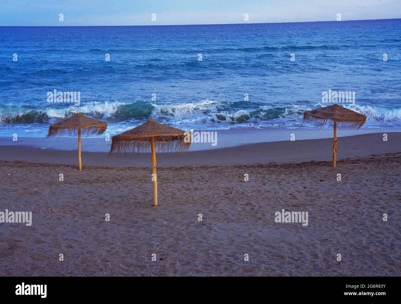 Drei Sonnenschirme an einem einsamen Strand. Stockfoto