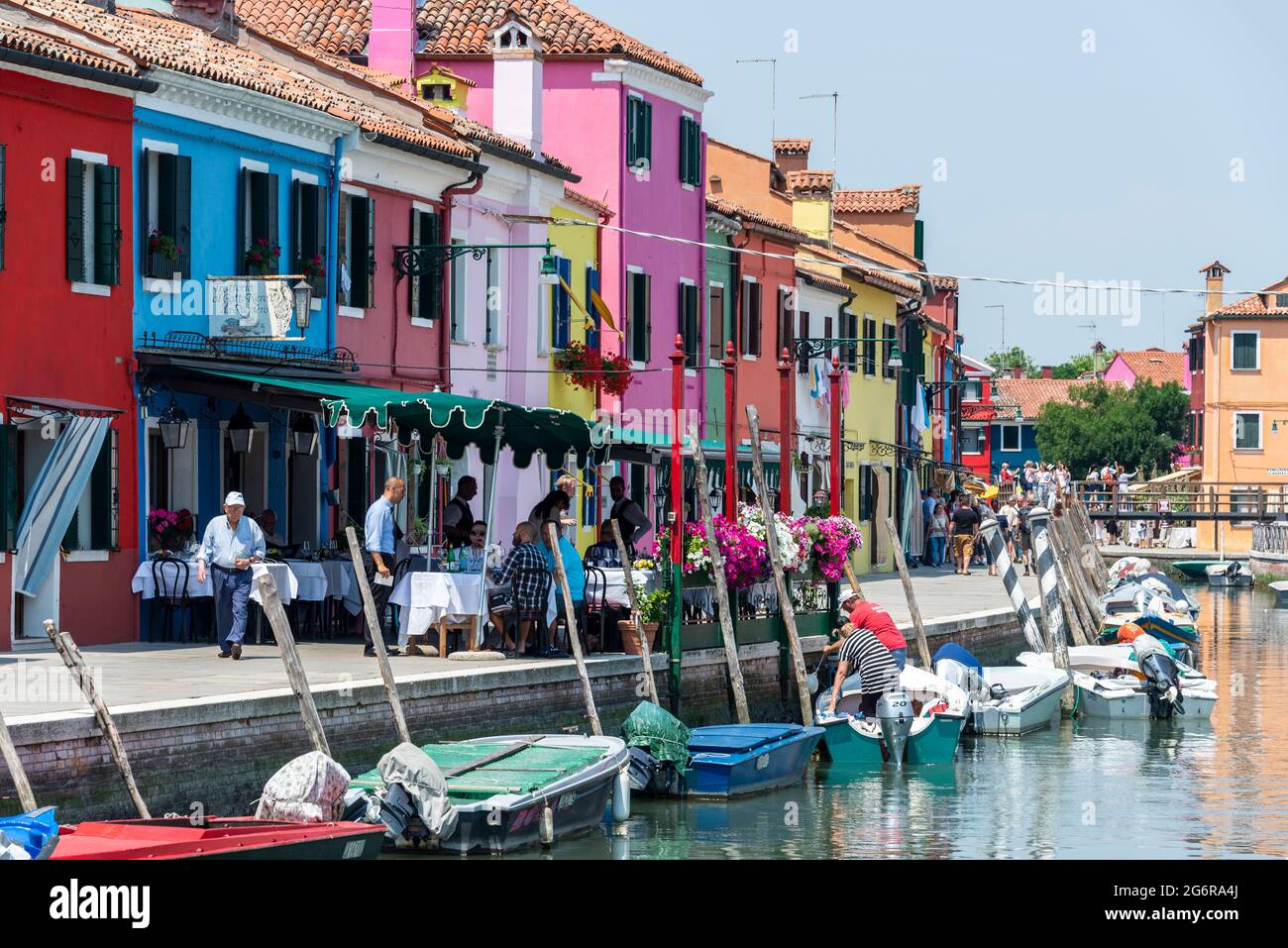 Ein belebtes Restaurant neben einem Kanal im kleinen Fischerdorf und kleinen Hafen von Burano, auf einer Insel in der Lagune von Venedig, etwa 7 km von Venedig entfernt Stockfoto