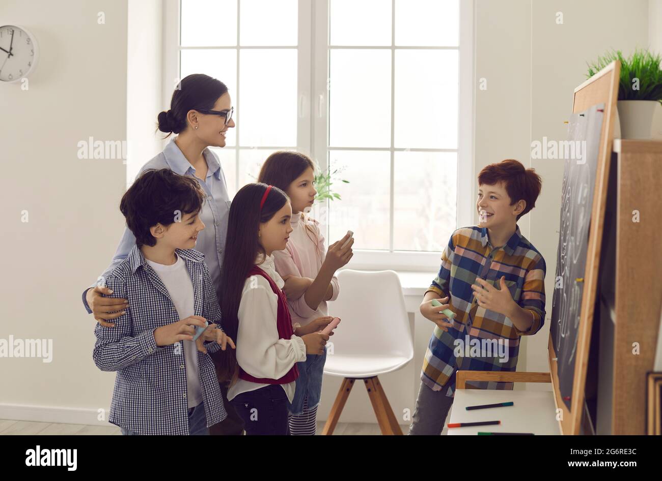 Der Schüler antwortet an der Tafel vor dem Lehrer und Klassenkameraden Stockfoto