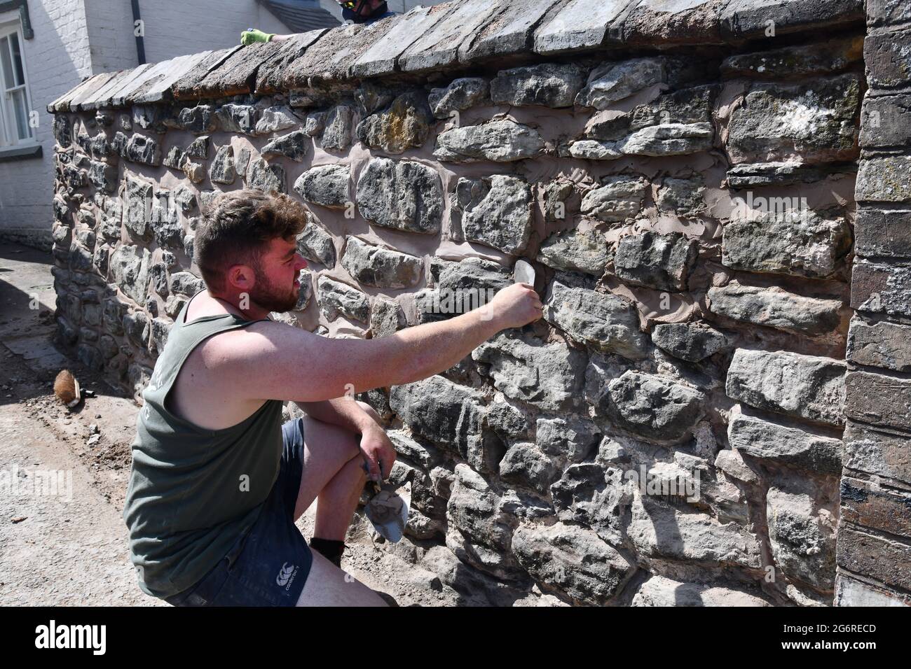 Bauarbeiter Baumeister Reparatur zeigen alte Steinmauer Großbritannien Stockfoto