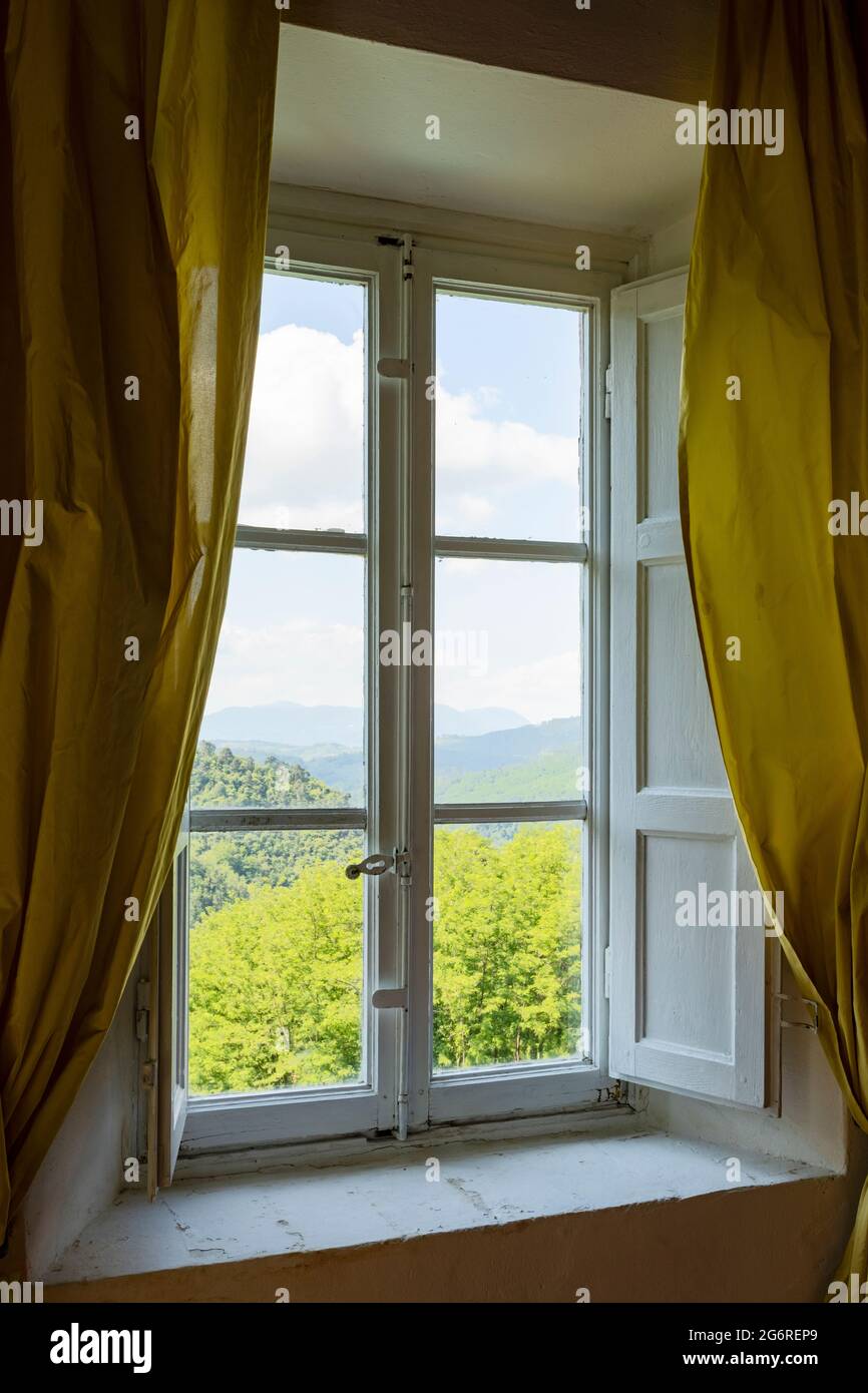 Fenster von innen gesehen auf einer grünen und romantischen Landschaft. Konzeptuelle Fotografie schaut weg Stockfoto