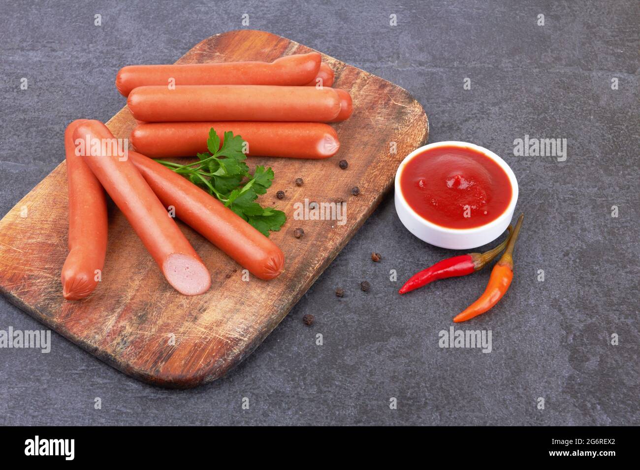 Rohe frankfurter Würstchen mit Ketchup auf Schneidebrett Stockfoto