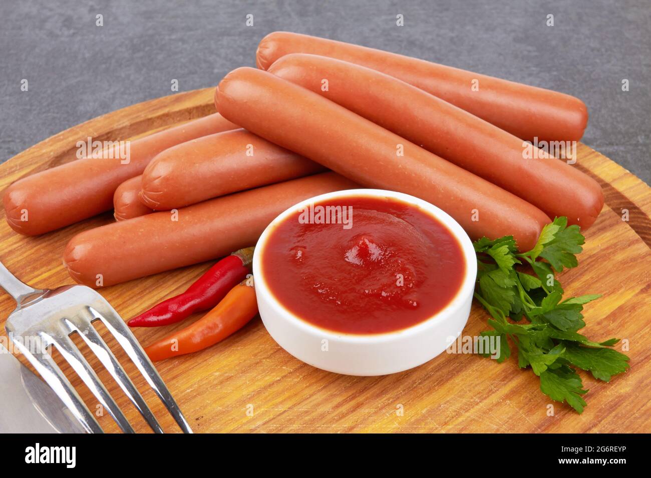Rohe frankfurter Würstchen mit Ketchup auf Schneidebrett Stockfoto