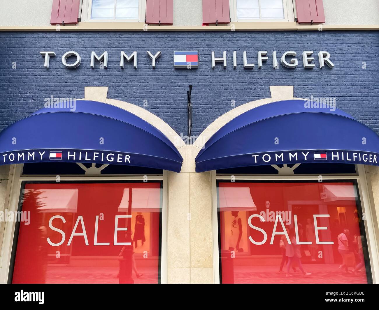 Roermond, Niederlande - 1. Juli. 2021: Blick auf die Ladenfassade mit Logo-Schriftzug von tommy hilfiger und roten Verkaufsschildern im Fenster (Fokus auf die Mitte der Gruppe Stockfoto