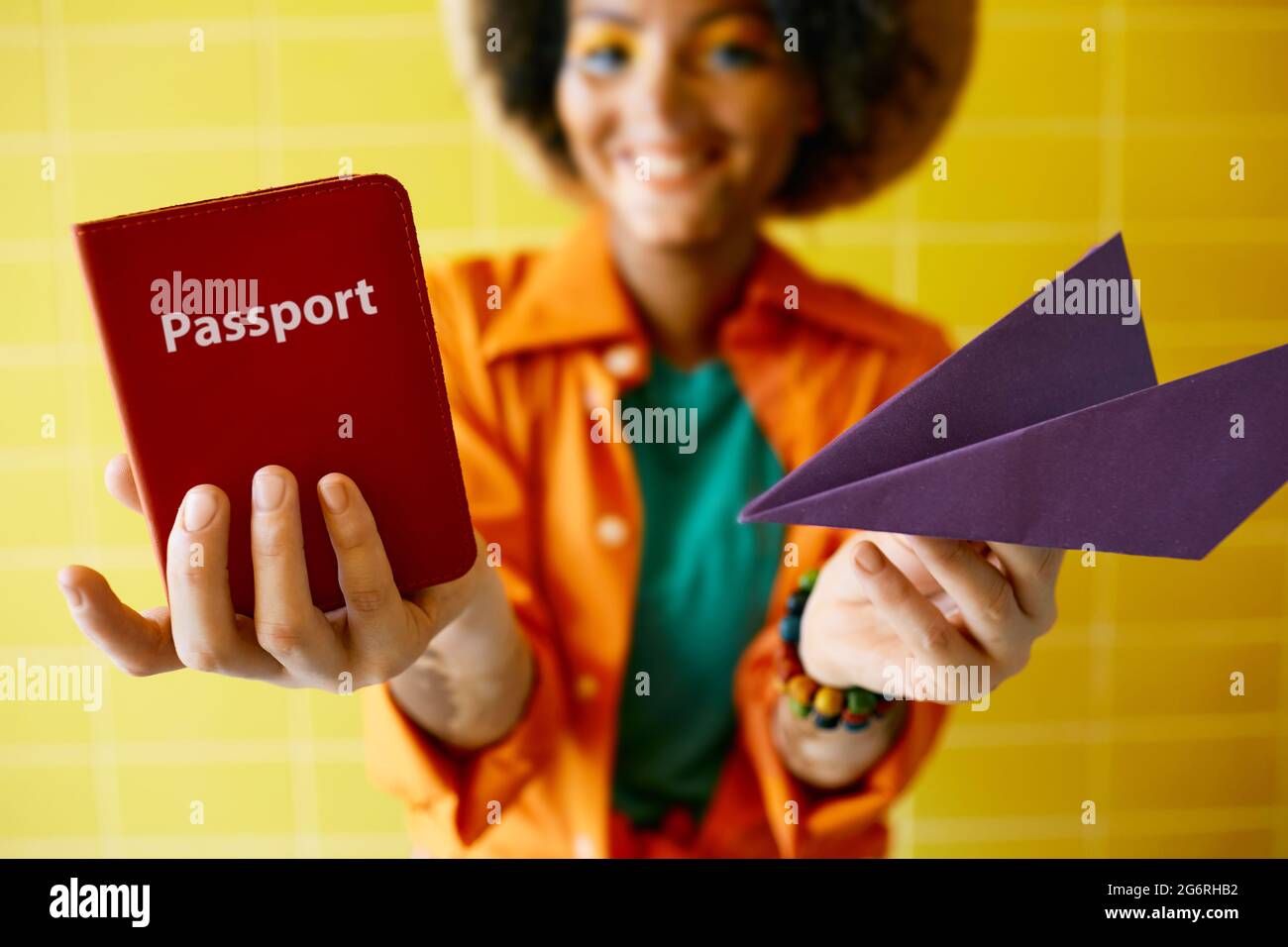 Internationaler Reisepass und Papierflugzeug in den Händen einer jungen Reisenden in der Nähe des Vordergrunds. Flugreisekonzept Stockfoto