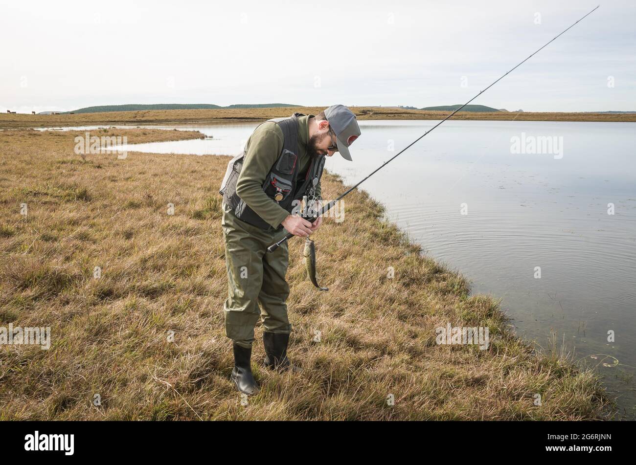 Sportfischer Angeln im See am bewölkten Tag Stockfoto