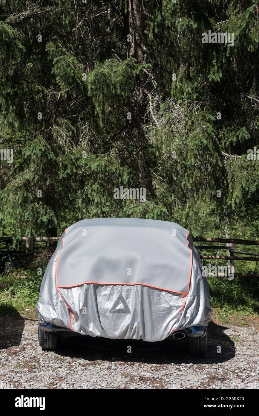 Die graue und silberne Sonnenschutz Autoabdeckung. Auto im Wald Parkplatz  mit einer Abdeckung zum Schutz vor Sonne und Staub geparkt Stockfotografie  - Alamy