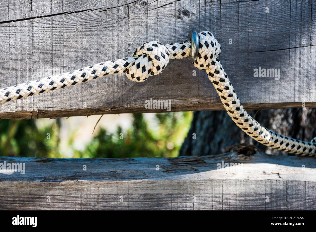 Ein schwarz-weißes Seil mit zwei Knoten als Geländer auf einem steilen Bergweg Stockfoto