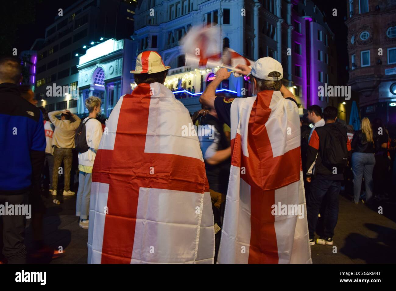 Englische Fußballfans, die in englische Flaggen gehüllt sind, feiern den Sieg Englands über Dänemark beim Halbfinale der Euro 2020 auf dem Leicester Square.Tausende jubelnder Fans versammelten sich im Zentrum Londons, um Englands Platz beim Finale der Fußball-Europameisterschaft 2020 zu feiern. Stockfoto