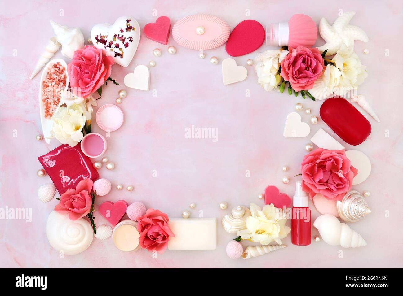 Beauty-Spa-Behandlungsprodukte für Haut- und Körperpflege mit Rosen- und Freesiablüten, die einen abstrakten Hintergrund bilden. Flache Laie in meliertem Pink. Stockfoto