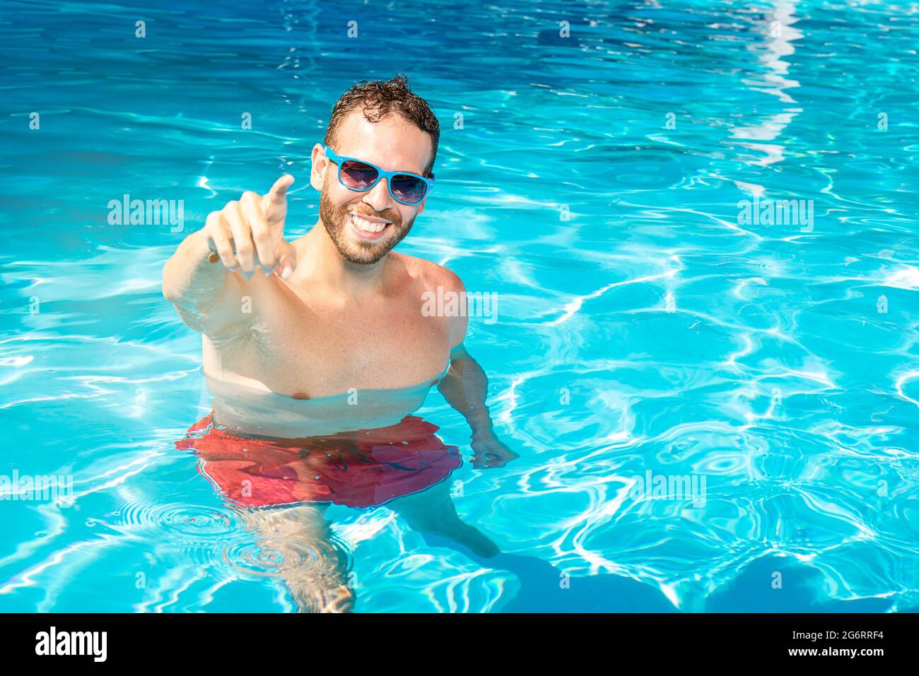 Der junge kaukasische Mann hat Spaß im Pool Stockfoto