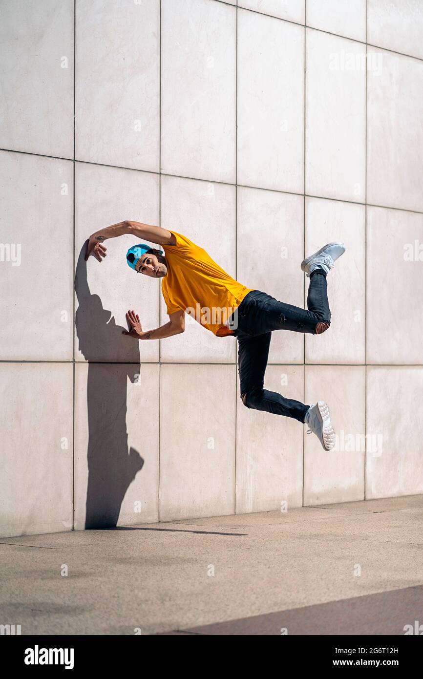 Selbstbewusster kleiner Junge, der Breakdance macht, tanzt auf der Straße gegen die weiße Wand. Stockfoto