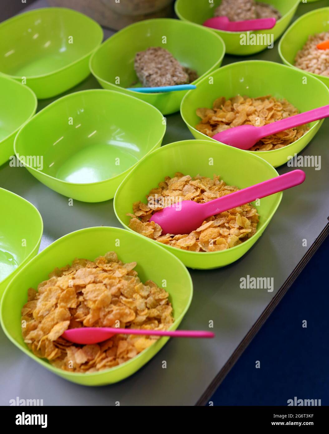 Cornflakes in Plastikschüsseln in einem Kinderschule-Frühstücksclub. Stockfoto
