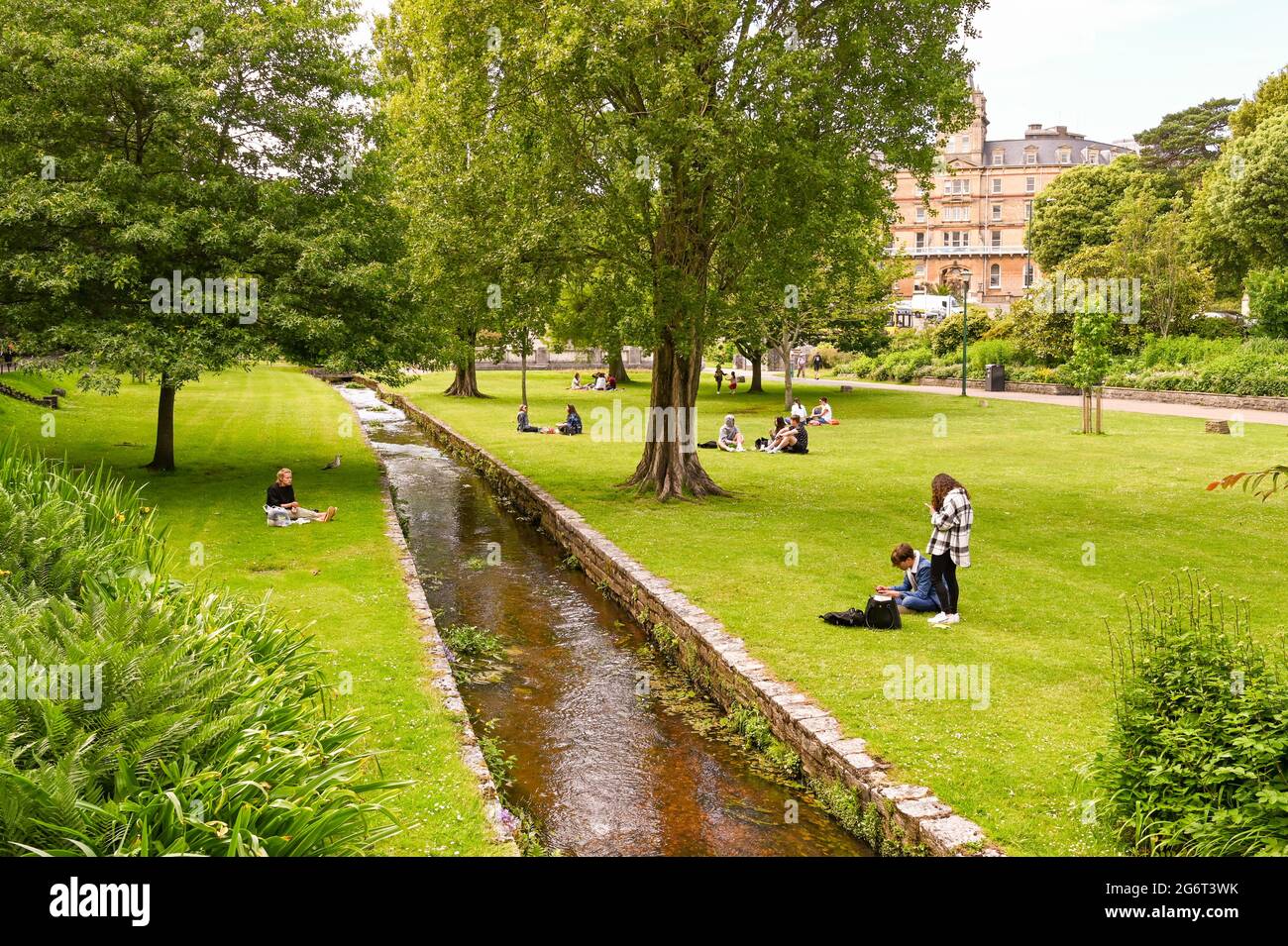 Bournemouth, England - 2021. Juni: Menschen entspannen sich am Bach, der durch den Lower Gardens Park der Stadt fließt. Stockfoto