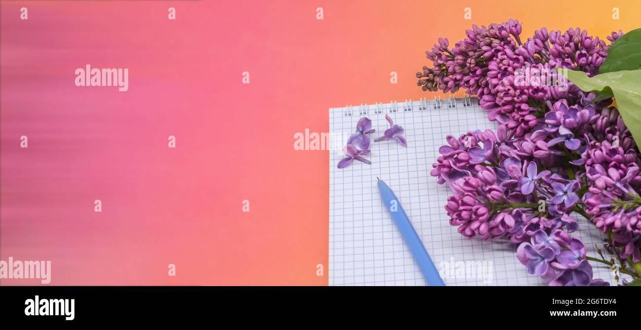 Spiralnotizbuch und Stift. Notizblock mit Stift und Blumen. Notebook-Flieder auf rotem Hintergrund. Stockfoto