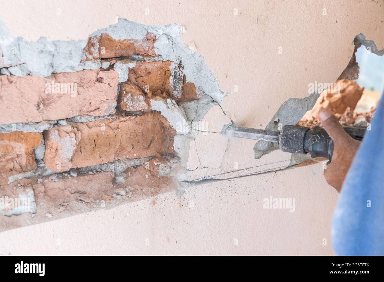 Arbeiter verwenden Abbruchhammer Bohrer, um die Wandoberfläche zu brechen. Bewegungsunschärfe beabsichtigt. Stockfoto